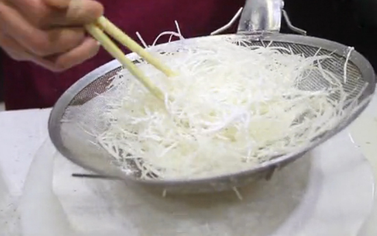 在切好的土豆丝上加入淀粉进行搅拌——贵阳新东方烹饪学校